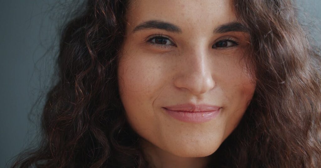 pexels-photo-36763544-36763544 Primer plano de una mujer con cabello rizado y una sonrisa cálida.